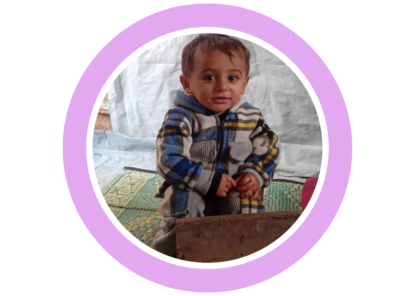 Aseel’s young child sitting inside a tent