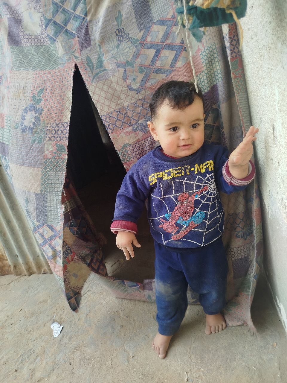 Noorhan’s young child standing by a tent